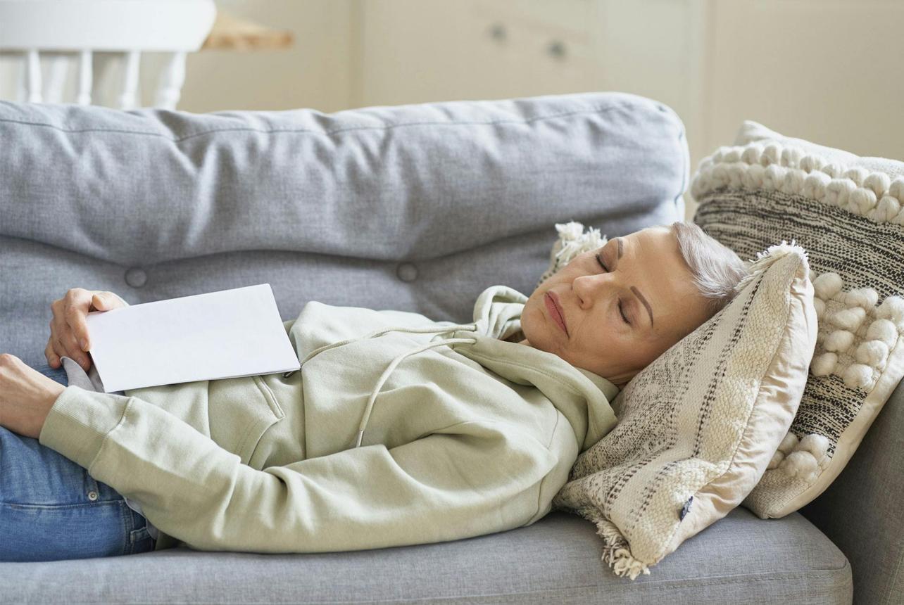 Woman resting on a sofa, conserving energy during recovery