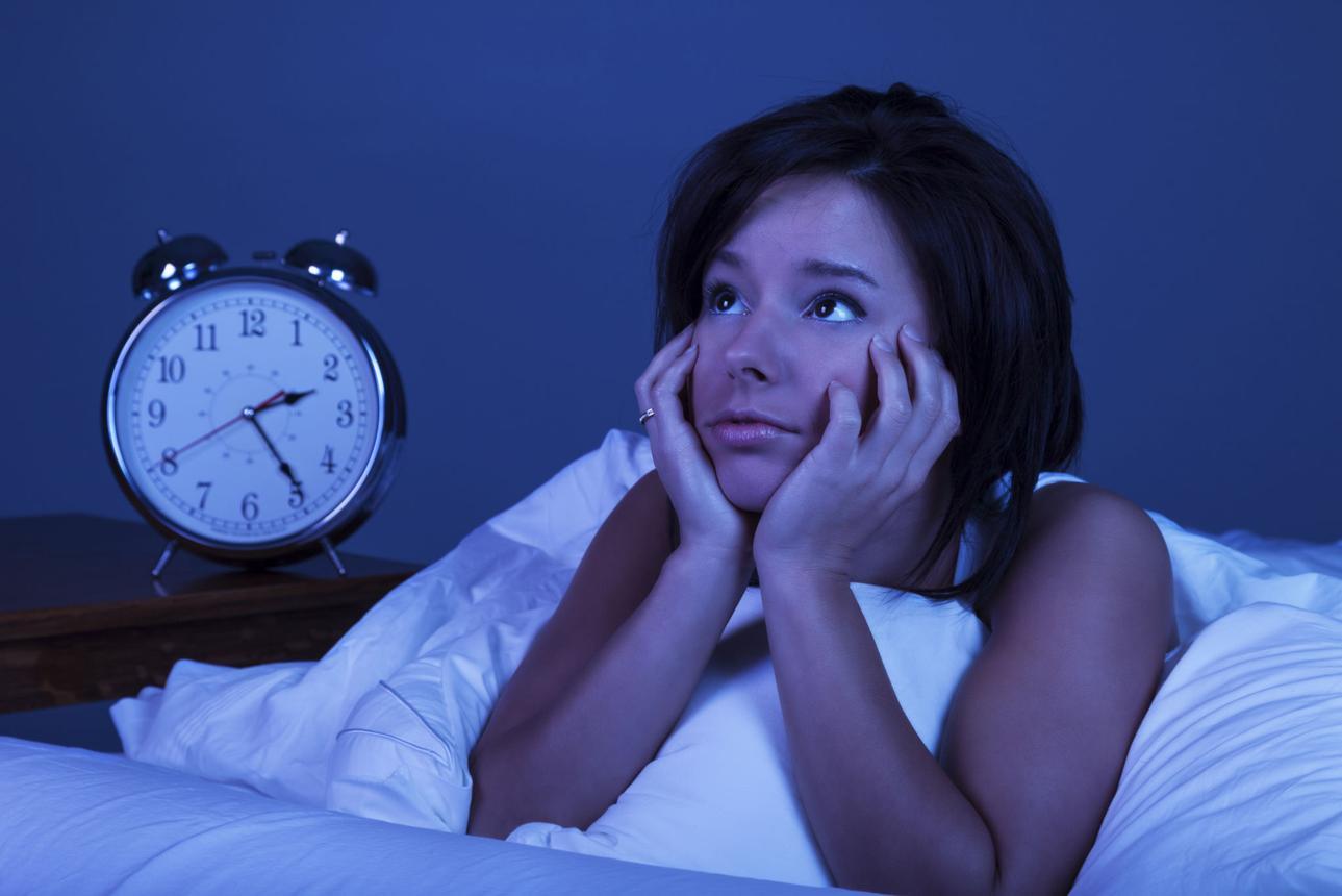 Woman lying awake in bed at night, struggling with sleep